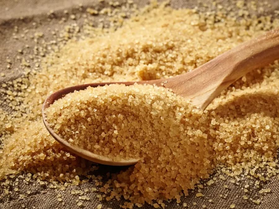 Raw brown sugar with a wooden scoop